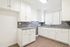 Bright and modern kitchen with sleek white cabinets, elegant gray countertops, and stylish backsplash.