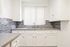 Bright and modern kitchen with sleek gray countertops, elegant white cabinetry, and stylish mosaic tile backsplash.