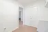 Bright, minimalist hallway with white walls and sleek wooden flooring leading to spacious rooms.