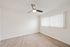 Bright and airy empty room featuring sleek laminate flooring, modern ceiling fan, and large window with vertical blinds, perfect for customization.