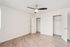 Bright and spacious bedroom with elegant hardwood flooring, sleek ceiling fan, and ample closet space.
