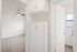 Bright hallway featuring elegant white cabinetry, leading to a room with modern ceiling fan, and adjacent bathroom with natural light.