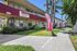 Inviting apartment complex with lush greenery and vibrant 'Now Leasing' signs, offering comfortable living on Roxanne Avenue.
