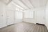 Bright and airy room with vaulted ceiling, featuring modern wood flooring and large windows with vertical blinds.