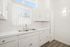 Bright and airy kitchen with elegant white cabinetry, sleek countertops, and modern dual sink framed by natural light from generous windows.