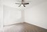 Bright and airy room with sleek wood flooring and a modern ceiling fan, offering an inviting blank canvas for personalization.