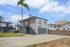 Charming two-story apartment building with modern exterior, lush palm tree, and convenient parking area.