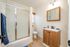Bright, modern bathroom with sleek glass shower, elegant wood vanity, and polished fixtures, offering a serene and stylish space.