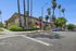 Charming residential building with stone façade and lush landscaping, lined with palm trees and situated on a sunny corner.