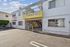 Charming apartment building with a bright yellow awning and secure gated entry, offering convenient parking.