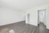 Sleek and spacious living area with elegant wood flooring, ample natural light, and crisp white walls, leading to a bright bathroom.