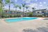 Charming apartment complex featuring a sparkling outdoor pool surrounded by lush palm trees and modern two-story buildings.