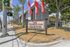 Inviting entrance to Westland @ Artesia in sunny Long Beach, CA, featuring vibrant red flags, lush palm trees, and a welcoming sign.