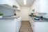 Contemporary kitchen with sleek white cabinetry and modern appliances, featuring stylish gray countertops and elegant wood flooring.