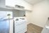 Bright kitchen with sleek white cabinets and stove, open layout leading to a sunlit room with sliding glass doors and stylish flooring.