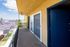 Bright and inviting balcony with yellow walls, overlooking serene jacaranda trees and a peaceful street.
