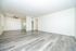 Bright and spacious living area with modern wooden flooring, open kitchen, and sleek ceiling fan.