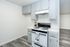 Modern kitchen with sleek grey cabinets, a pristine white gas stove, and elegant wood flooring for a stylish cooking space.