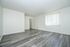 Bright and spacious room with modern grey laminate flooring, white walls, and a large window with vertical blinds.