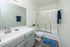 Inviting bathroom with sleek fixtures, elegant tiled vanity, and glass-enclosed shower. Bright and modern design with a touch of greenery.