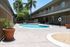 Inviting apartment courtyard featuring a shimmering round swimming pool surrounded by lush palm trees and a secure fence, perfect for relaxation and leisure.