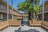 Charming courtyard view showcasing modern apartment complex, lush greenery, and inviting pool.