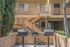 Charming apartment with outdoor grill area, lush greenery, and inviting stairs leading to the upper units.