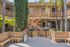 Inviting apartment courtyard with lush greenery, barbecue grills, and cozy seating under palm trees.