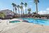 Inviting outdoor pool and spa area surrounded by palm trees, perfect for relaxation in a sunny residential community.