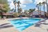 Inviting pool area surrounded by picturesque palm trees and a sunlit patio in a serene apartment complex.