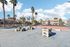 Vibrant outdoor recreation area featuring palm trees, a tennis court, and a foosball table under a clear blue sky.