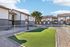 Charming apartment complex with tiled roofs, communal green space, and inviting outdoor seating area.