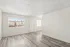 Bright and airy living space with modern hardwood flooring, enhanced by natural light through large windows.