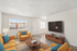 Bright and modern living room with vibrant yellow sofas, stylish decor, and a large wall-mounted TV, perfect for relaxing.