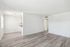 Bright and airy open living space with modern hardwood floors, inviting natural light through large windows, and a glimpse of the sleek kitchen area.