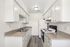 Bright, galley-style kitchen with modern white cabinets, sleek countertops, and a functional layout.