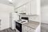 Modern kitchen with sleek white cabinetry, electric stove, and spacious countertops in a bright, inviting space.
