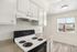Bright kitchen with modern white cabinetry, electric stove, and a large window for natural light.