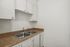 Modern kitchen with sleek countertops and stainless steel double sink, complemented by bright white cabinetry for a fresh and clean look.