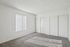 Bright and spacious empty room with plush carpeting, vertical blinds, and ample closet space.