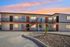 Charming apartment building with warm lighting and sunset skies, featuring distinct orange-accented entrances and a modern exterior.