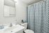 Charming bathroom with elegant blue and white patterned shower curtain, sleek vanity, and contemporary fixtures.