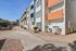 Vibrant, modern apartment complex exterior with colorful facades, large windows, and lush greenery along a welcoming, sunlit pathway.