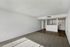Bright and airy open-concept living space with stylish carpeting and sleek hardwood floors leading to a modern kitchen with white cabinetry.