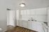 Bright, modern kitchen with sleek white cabinetry, dual sink, and classic wood flooring.