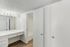 Elegant bathroom with sleek white cabinets, modern lighting, and wood flooring for a sophisticated look.