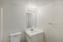 Bright and modern bathroom featuring elegant white decor, a sleek vanity with under-sink storage, and stylish overhead lighting.