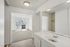 Inviting apartment hallway leading to a bright room with balcony access, featuring elegant hardwood floors and a sleek modern sink.