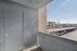 Bright and spacious apartment balcony with a view of parking and contemporary architecture, perfect for enjoying sunny days.