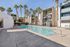 Inviting apartment complex with a sparkling swimming pool, surrounded by palm trees and modern architecture, perfect for relaxation and leisure.
